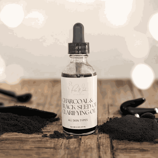 Charcoal & Black Seed Clarifying Oil bottle on a wooden surface with black powder.